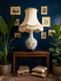 Grande lampe de parquet vintage composée d'un vase en porcelaine blanche décoré de fleurs et d'oiseaux (style Famille Rose), sur un socle en bois foncé. L'abat-jour en lin est orné de franges colorées.