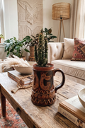 Grande chope en céramique d'art émaillée couleur marron avec motifs géométriques et volutes gravés en relief, signée Beny Leleu sous la base, style poterie artisanale des années 1970 utilisée comme cache-pot pour un cactus.